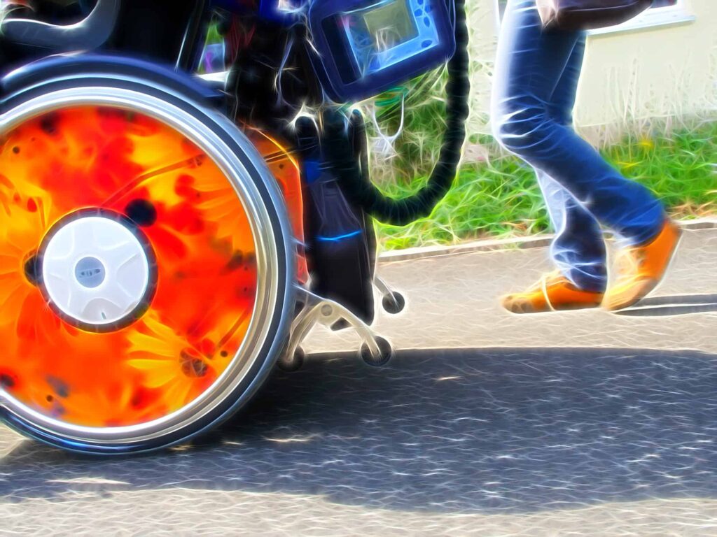 Pflegefachkraft mit Rollstuhl, Monitor und Beatmung unterwegs