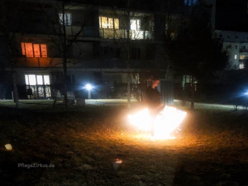Frau tanzt mit Feuer im Hinterhof in Jena am dunklen Abend